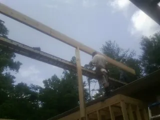 Carpenter setting a ridge beam over a new addition frame — Ice Dam Removal by Roofing Brothers in Tyler Hill
