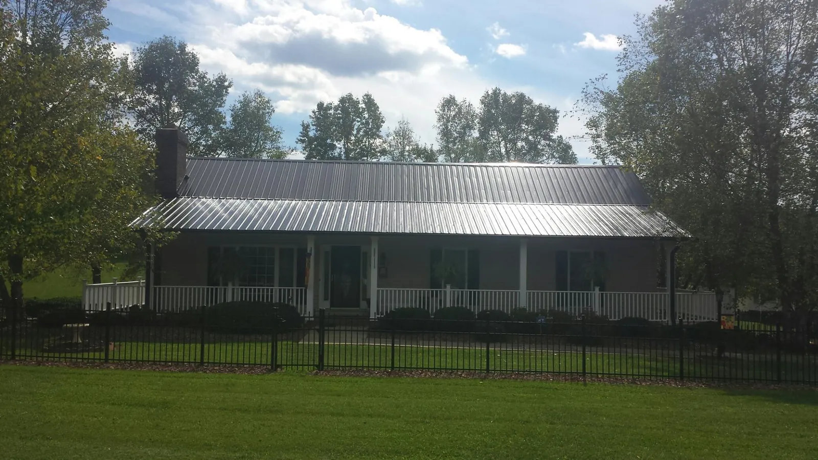 Gray metal roof on a brick ranch with a full width front porch — Gutter Guard Installation work by our crew in Tyler Hill